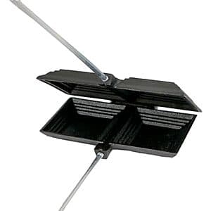 Coghlan's black cast iron double camp cooker with two cooking surfaces and handles.