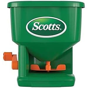 Scotts Whirl hand-powered grass seed spreader with red and yellow plastic body, hopper top, and hand crank mechanism.