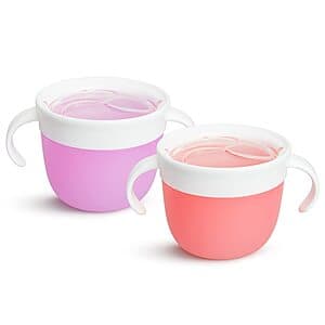 Two Munchkin Snack Catcher cups in pink and purple with soft flexible flaps on lids, designed for toddler snack storage.